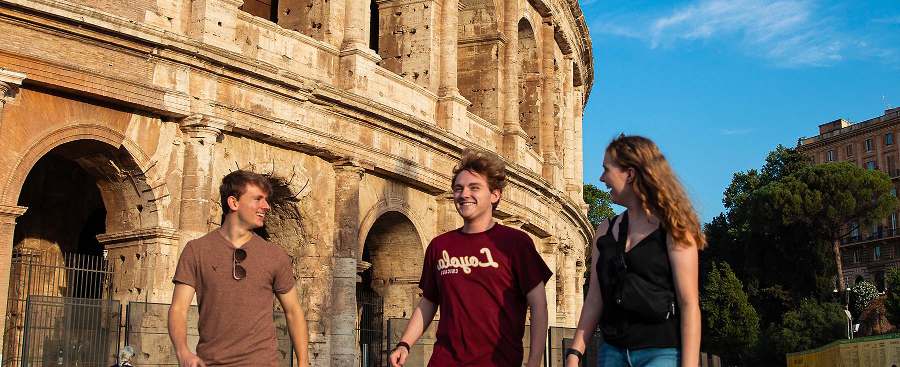 Loyola students walk next to the iconic Rome Coliseum